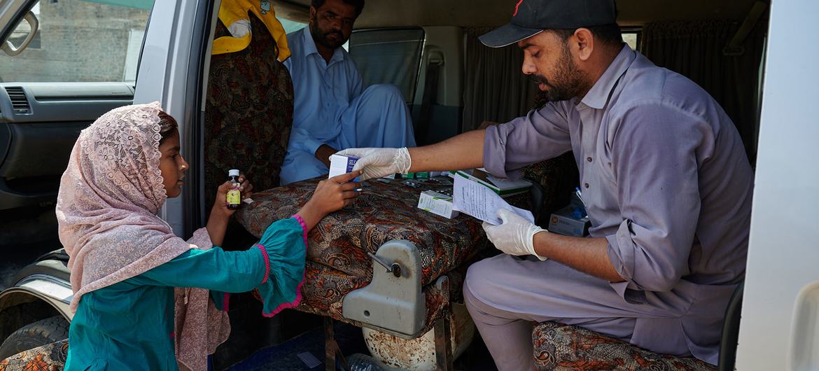 A young girl collects her medication from a mobile health unit set up for flood victims in Shangar District, Pakistan.