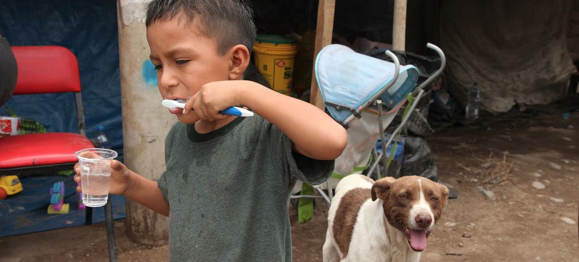 A displaced boy, whose home was destroyed by floods, brushes his teeth outside a temporary shelter in Lima, Peru.