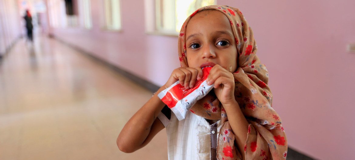 A small girl eats a peanut-based paste while being treated for malnutrition at a hostpial in Sa'ana, Yemen.
