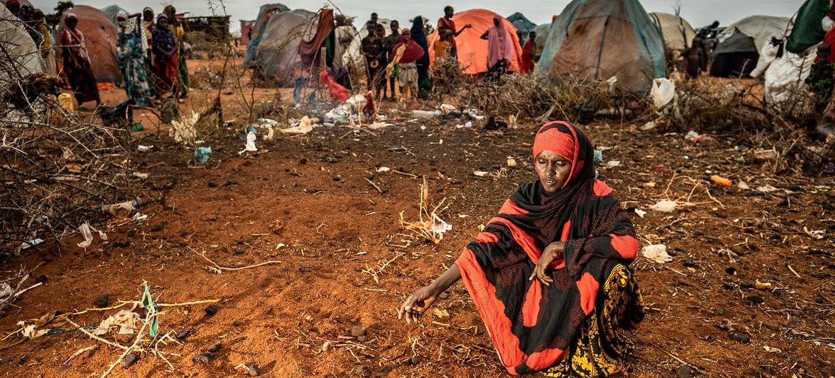 A mother sits at the unmarked graves of her two young children in a displaced persons camp in Dollow, Somalia.