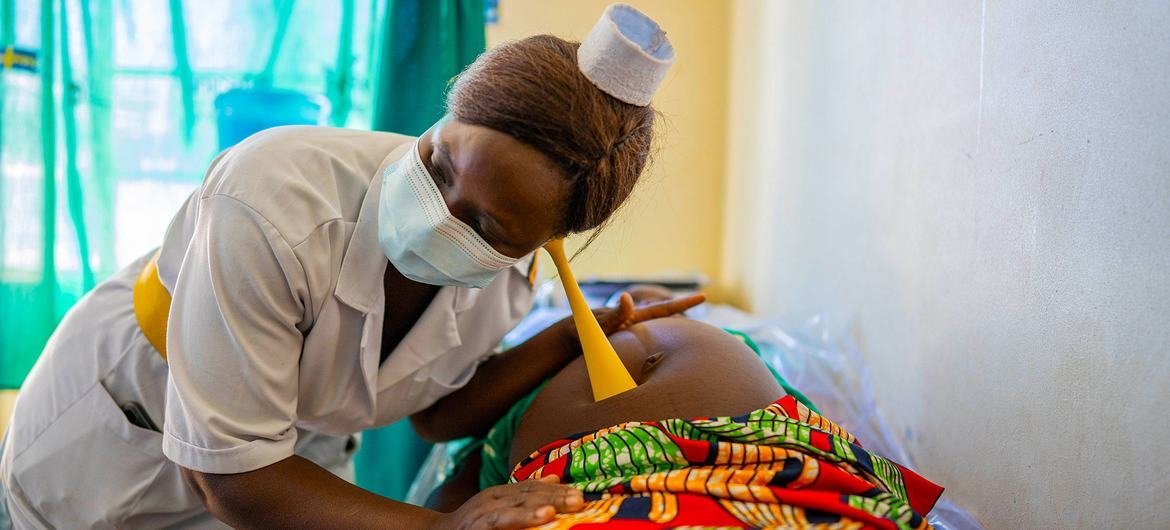 A nurse examines a pregnant mother during an antenatal care visit at a health centre in Uganda.