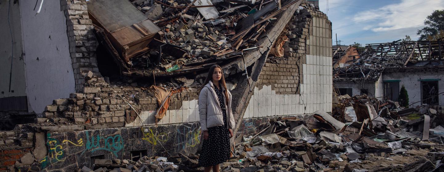 A Ukrainian teenager stands in the rubble of her destroyed school in Zhytomyr.